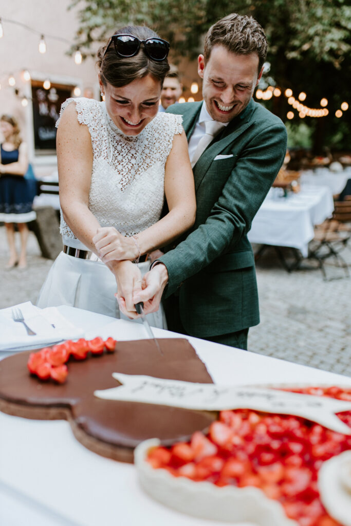 Brautpaar schneidet Hochzeitstorte an im Wirtshaus Ayinger in der Au